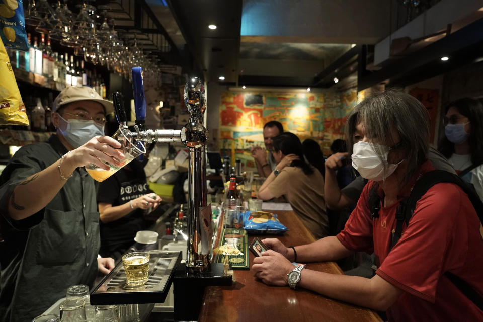 In this Oct. 9, 2020 photo, former lawmaker and pro-democracy activist Leung Kwok-hung, known as "Long Hair," right, waits for his drink at Club 71 in Hong Kong. The bar known as a gathering place for pro-democracy activists and intellectuals is closing. For years, the storied bar has served as a watering hole for the city’s pro-democracy activists and intellectuals, who could freely engage in discussions over a round of beer or two. (AP Photo/Kin Cheung)