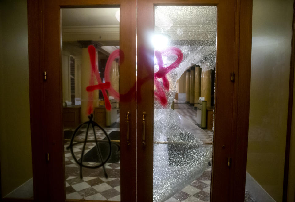 Graffiti is sprayed on a damaged door at City Hall in Portland Ore., on Tuesday, Aug. 25, 2020. Officials say protesters in Portland smashed windows at City Hall in a demonstration that started Tuesday night and stretched into Wednesday morning. (Dave Killen/The Oregonian via AP)