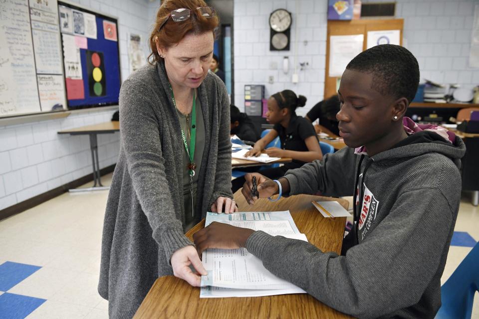 In this Nov. 7, 2019, photo, Crosby High School algebra teacher Jennifer Desiderio works with Lyndon Frederic, right, in her class in Waterbury, Conn. While students in the Waterbury public school district are predominantly black and Hispanic, the vast majority of its educators, as in school districts across the country, are white. (AP Photo/Jessica Hill)