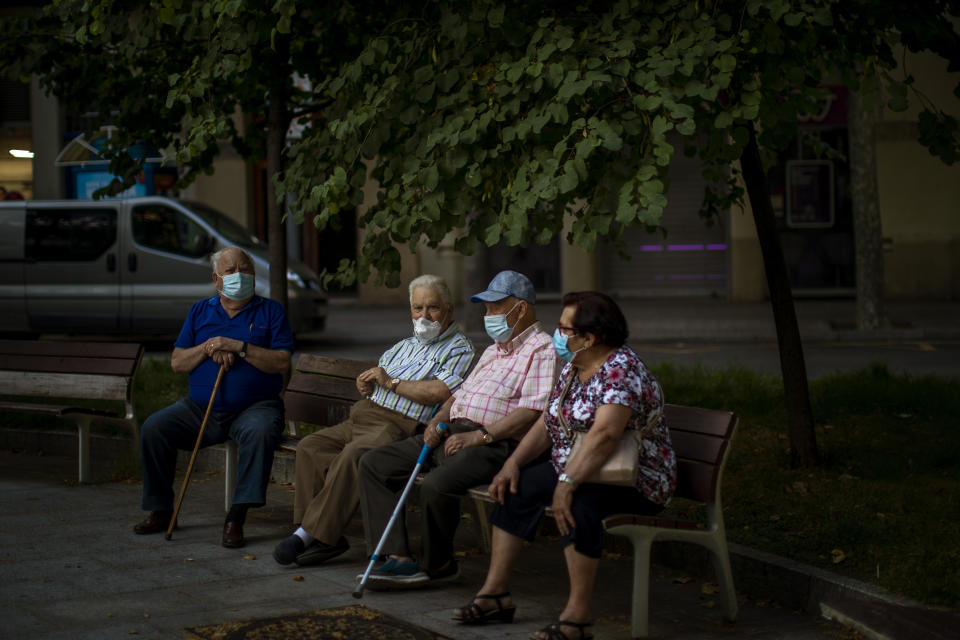 Elder people wearing face masks sit on a bench in a square in Barcelona, Spain, Sunday, May 31, 2020. Spanish Prime Minister Pedro Sánchez says he will ask Spain's Parliament for a final two-week extension of the nation's state of emergency that has allowed the government to take lockdown measures to control its coronavirus outbreak. (AP Photo/Emilio Morenatti)