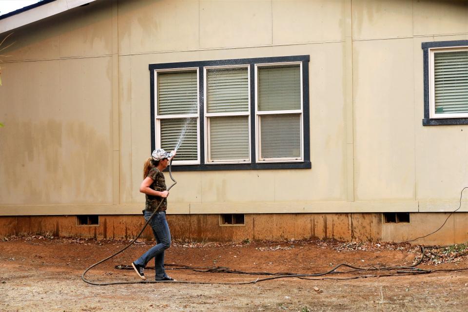 Katie Wright hoses down a family home on Casa Drive in an evacuated neighborhood about a half-mile from the Fawn Fire on Thursday, Sept. 23, 2021.