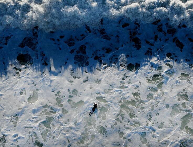 Huntington Beach, CA - January 04: A surfer struggles to paddle against strong currents and through large breaking waves in Huntington Beach created by an approaching storm that will impact Southern California Thursday, Jan. 4, 2024. (Allen J. Schaben / Los Angeles Times)