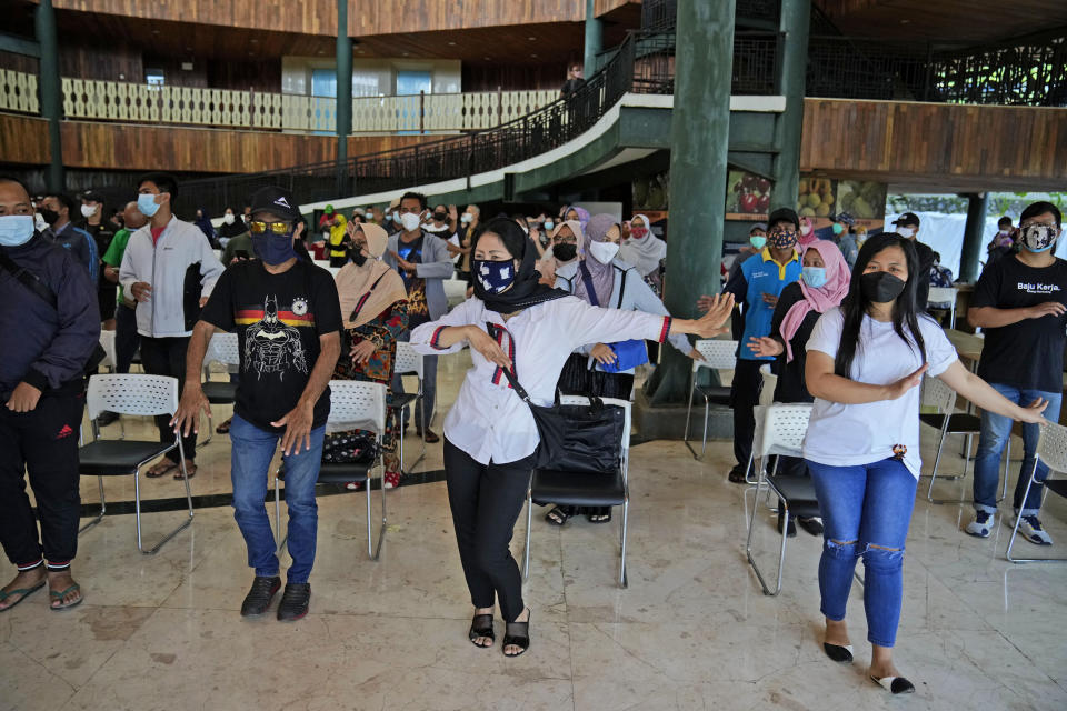 People dance to the music played by organizer while they wait to receive the Sinovac COVID-19 vaccine during a mass vaccination in Jakarta, Indonesia, Monday, June 21, 2021. Indonesia's president ordered authorities to speed up the country's vaccination campaign as the World Health Organization warned of the need to increase social restrictions in the country amid a fresh surge of coronavirus infections caused by worrisome variants. (AP Photo/Dita Alangkara)