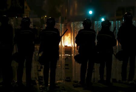 Riot police stand guard in front of a fire set by protesters at a junction in Mongkok district in Hong Kong, China February 9, 2016. REUTERS/Bobby Yip