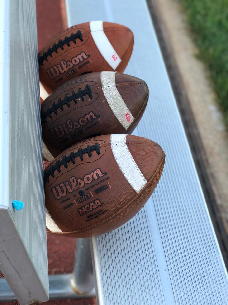 Footballs sit on a bench at DeWitt High School prior to a game on Sept. 14, 2018.