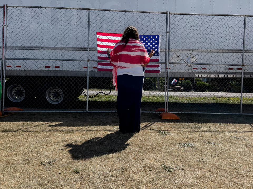 A woman prays as she faces a U.S. flag on the perimeter fence at the ReAwaken America Tour at Cornerstone Church in Batavia, N.Y., on Aug. 13, 2022.<span class="copyright">Carolyn Kaster—AP</span>