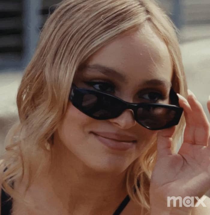 Lily-Rose Depp as Jocelyn from "The Idol" looking over her sunglasses as she smirks