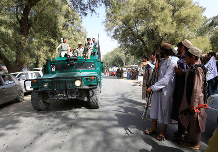 A Taliban (R) stands as Afghan security forces ride on an army vehicle during celebration ceasefire in Bati Kot district of Nangarhar province, Afghanistan June 16, 2018.REUTERS/Parwiz