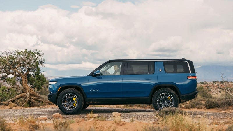 A photo of a blue Rivian R1S SUV in the countryside. 