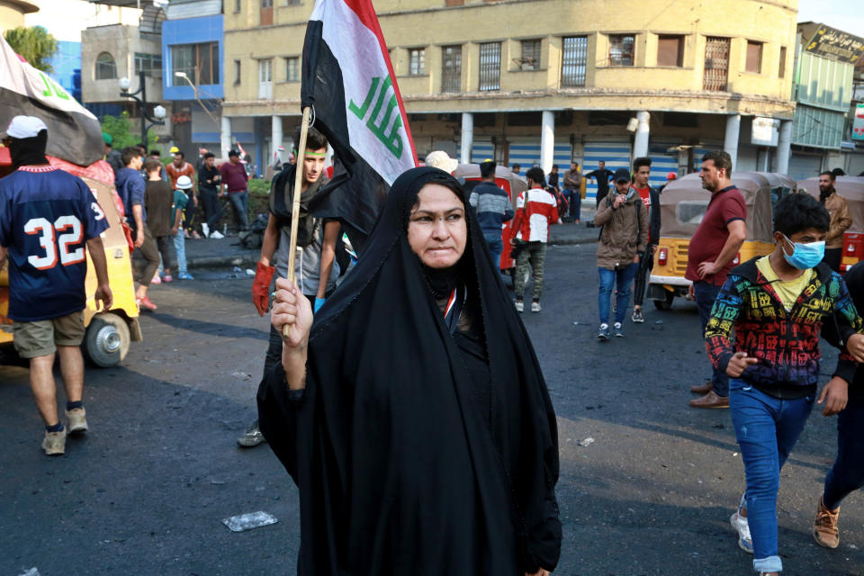 An Iraqi woman holds a national flag while anti-government protesters gather on Rasheed Street during ongoing protests in Baghdad, Iraq, Thursday, Nov. 28, 2019. Scores of protesters have been shot dead in the last 24 hours, amid spiraling violence in Baghdad and southern Iraq, officials said. (AP Photo/Khalid Mohammed)