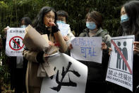 Zhou Xiaoxuan, second from left, walks by her supporters holding banners as she arrives at a courthouse in Beijing, Wednesday, Dec. 2, 2020. Zhou, a Chinese woman who filed a sexual harassment lawsuit against a TV host, told dozens of cheering supporters at a courthouse Wednesday she hopes her case will encourage other victims of gender violence in a system that gives them few options to pursue complaints. (AP Photo/Andy Wong)