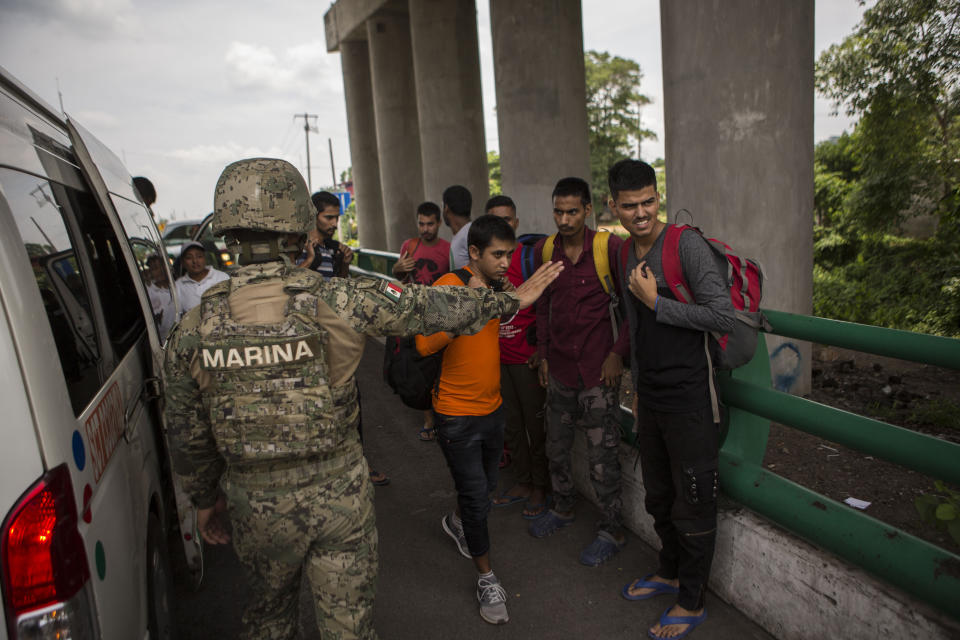 A Mexican Marine orders a group of migrants from Bangladesh, India and Pakistan to step back, at an immigration checkpoint known as Viva Mexico, near Tapachula, Mexico, Friday, June 21, 2019. Mexico's foreign minister says that the country has completed its deployment of some 6,000 National Guard members to help control the flow of Central American migrants headed toward the U.S. (AP Photo/Oliver de Ros)