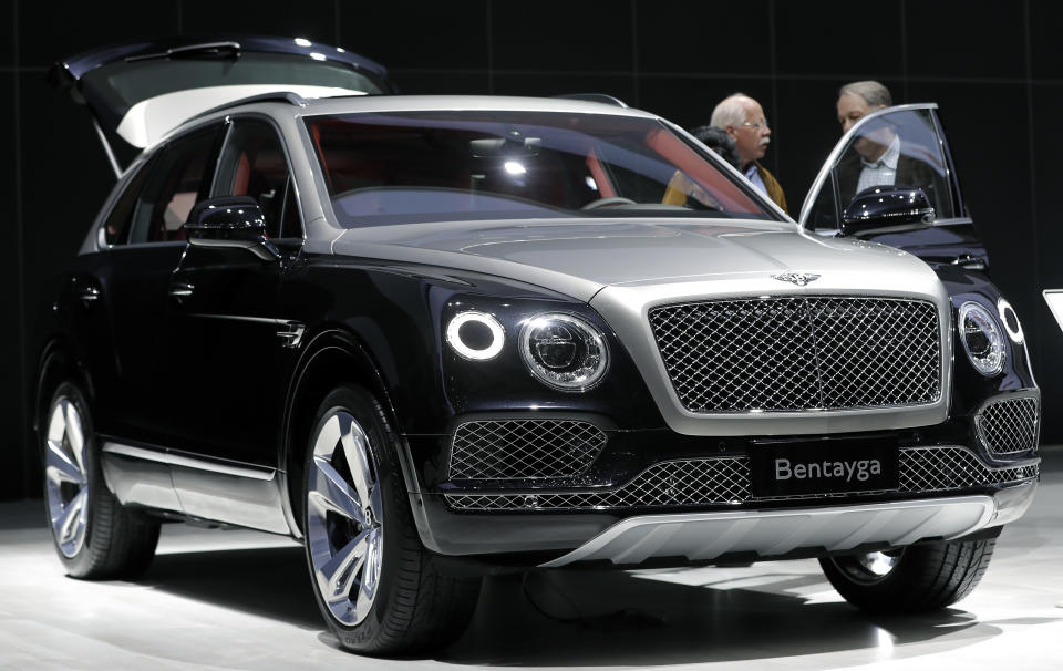 FILE - People stand at a Bentley Bentayga SUV car during the annual shareholders meeting of the Volkswagen AG in Hannover, Germany, Wednesday, May 10, 2017. Luxury automaker Bentley says it is pouring billions into upgrading manufacturing to accelerate its electric vehicle development plan, joining other auto brands shifting away from gasoline engines. U.K.-based Bentley Motors said Wednesday, Jan. 26, 2022 that it's investing 2.5 billion pounds ($3.4 billion) into sustainability efforts over the next decade. (AP Photo/Michael Sohn, File)