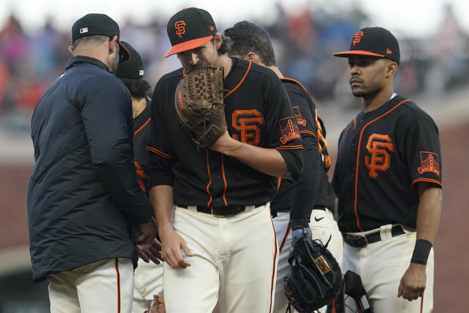 San Francisco Giants' Kevin Gausman, middle, walks off the mound after being taken out for a relief pitcher by manager Gabe Kapler, left, during the fifth inning of the team's baseball game against the Pittsburgh Pirates in San Francisco, Saturday, July 24, 2021. (AP Photo/Jeff Chiu)