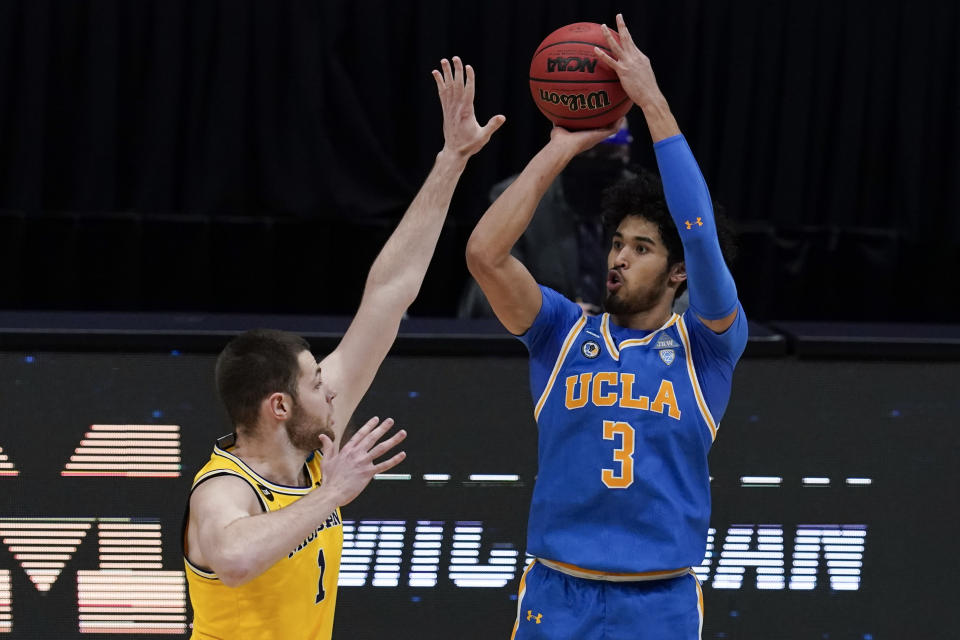 FILE - UCLA guard Johnny Juzang (3) shoots over Michigan center Hunter Dickinson (1) during the first half of an Elite 8 game in the NCAA men's college basketball tournament at Lucas Oil Stadium, Tuesday, March 30, 2021, in Indianapolis. Led by Juzang, the second-ranked UCLA Bruins return nearly everyone from last season's surprising Final Four run. They open the season at home against Cal State Bakersfield on Nov. 9. (AP Photo/Michael Conroy, File)