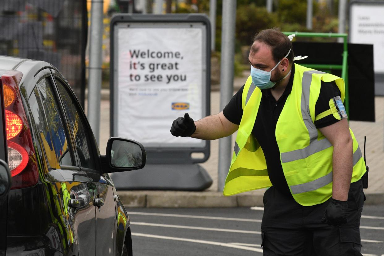 Stewards direct NHS staff visiting the drive-through COVID-19 testing centre set up at the car park of the Ikea store in Gateshead, northeast England on April 9, 2020 as Britain continued to battle the outbreak of new coronavirus and the governement prepared to extend the nationwide lockdown. - The disease has struck at the heart of the British government, infected more than 60,000 people nationwide and killed over 7,000, with another record daily death toll of 938 reported on April 8. A testing centre opened in Gateshead on April 9, 2020 as the government ramped up its testing of NHS staff for the new coronavirus. (Photo by Oli SCARFF / AFP) (Photo by OLI SCARFF/AFP via Getty Images)
