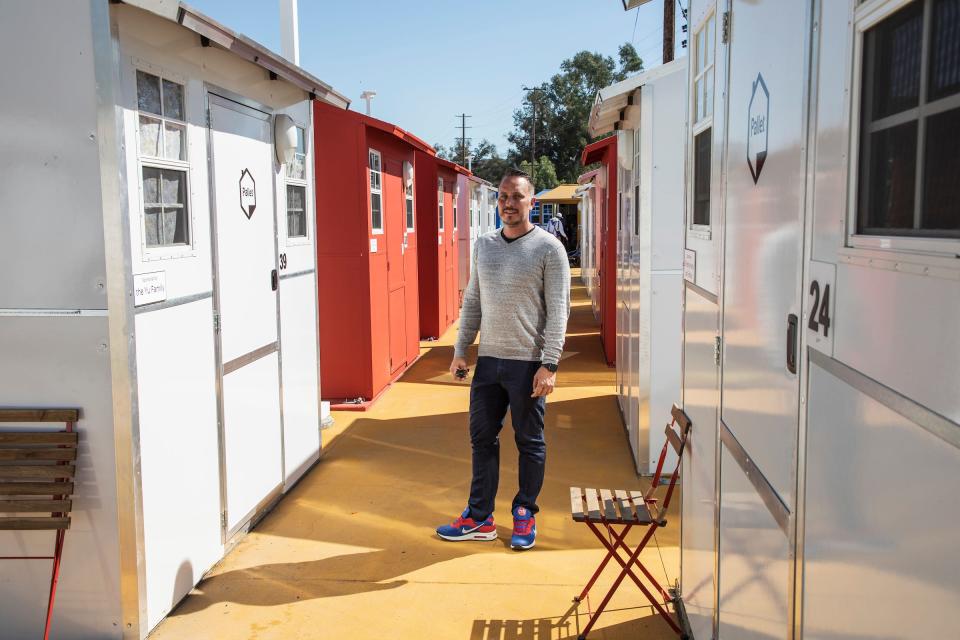 A man stands in the walkway between some of the tiny homes.