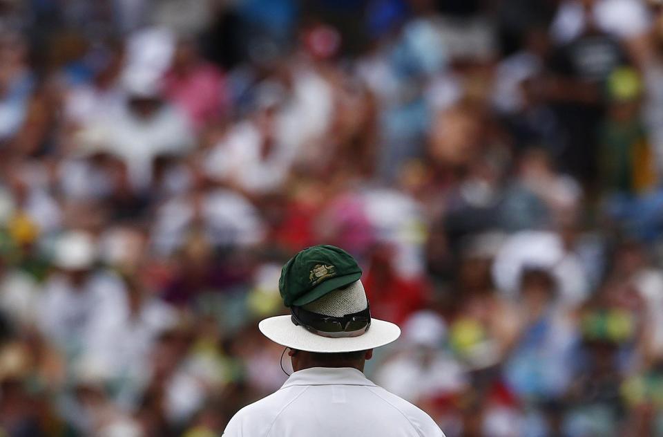 Australia's Nathan Lyon's cap is seen on umpire Marais Erasmus's hat as he bowls during the fourth day of the second Ashes test cricket match against England at the Adelaide Oval December 8, 2013.