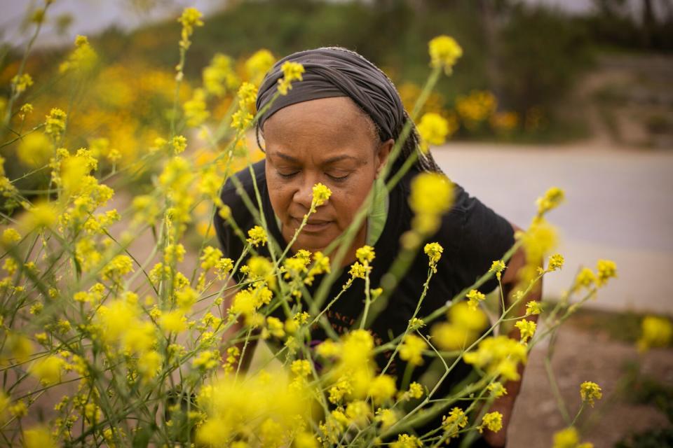 Surrounded by yellow wildflowers and mustard plants Deneen Vaughn stops to catch her breath