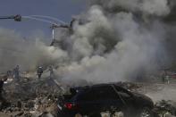 Firefighters extinguish flames as smoke rises from Surmalu market about two kilometers (1.2 miles) south of the center Yerevan, Armenia, Sunday, Aug. 14, 2022. A strong explosion at a fireworks storage area has ripped through a market in Armenia's capital. At least one person has been killed and about 20 others have been injured. The blast on Sunday set off a large fire. (Vahram Baghdasaryan/Photolure via AP)