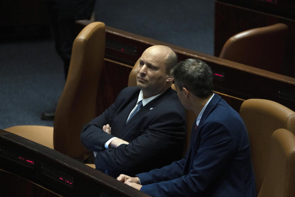 Israeli Prime Minister Naftali Bennett, left, speaks with Minister of Communications Yoaz Hendel during the opening of the summer session of the Knesset, Israel's parliament, in Jerusalem, Monday, May 9, 2022. Less than a year after taking office, Bennett has lost his parliamentary majority, his own party is crumbling and a key governing partner has suspended cooperation with the coalition. That has set the stage for a possible attempt by the opposition, led by former Prime Minister Benjamin Netanyahu, to topple the government later this week. (AP Photo/Maya Alleruzzo)