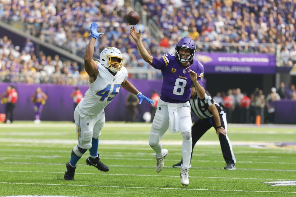 Minnesota Vikings quarterback Kirk Cousins (8) throws a pass under pressure by Chargers linebacker Tuli Tuipulotu.