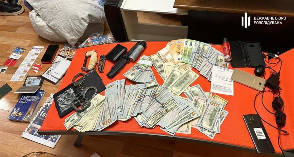 A photo of items seized from the lieutenant colonel's home include knives, a knuckle duster, and stacks of foreign cash.