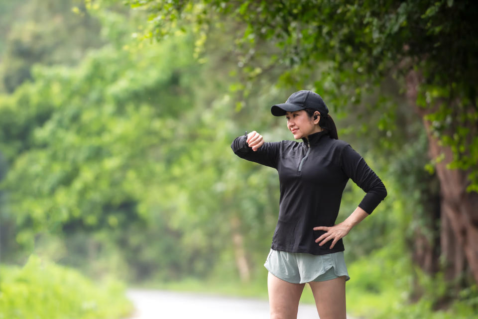 Persona observa su reloj mientras camina por un bosque