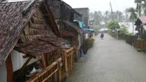 In this photo provided by the San Policarpo Firestation, a man wades through floodwater caused by Typhoon Surigae in the municipality of San Policarpo, Eastern Samar, eastern Philippines on Sunday April 18, 2021. An approaching typhoon has left at least one person dead, another missing and prompted the evacuation of more than 100,000 people as a precaution in the eastern and central Philippines, although the unusual summer storm is not expected to blow into land, officials said Monday. (FO1 Marianne Jabinal/ San Policarpo Firestation via AP)