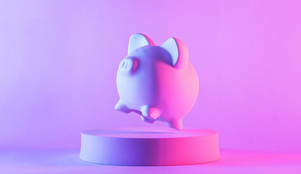 a piggy bank on a pedestal on a neon pink background