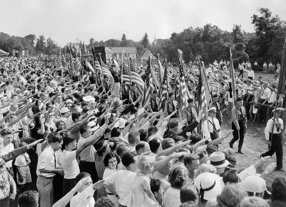 Hundreds of thousands of German-Americans sympathize with the Nazi Hitler Germany raises their hands in a Nazi salute to the passage of the German-American Bund with the German swastika flag and american flag during an annual "German Day" celebrated at Camp Siegfried in Yaphank on August 29, 1937 in Long Island, United States. (Photo by ACME / AFP) (Photo by -/ACME/AFP via Getty Images)