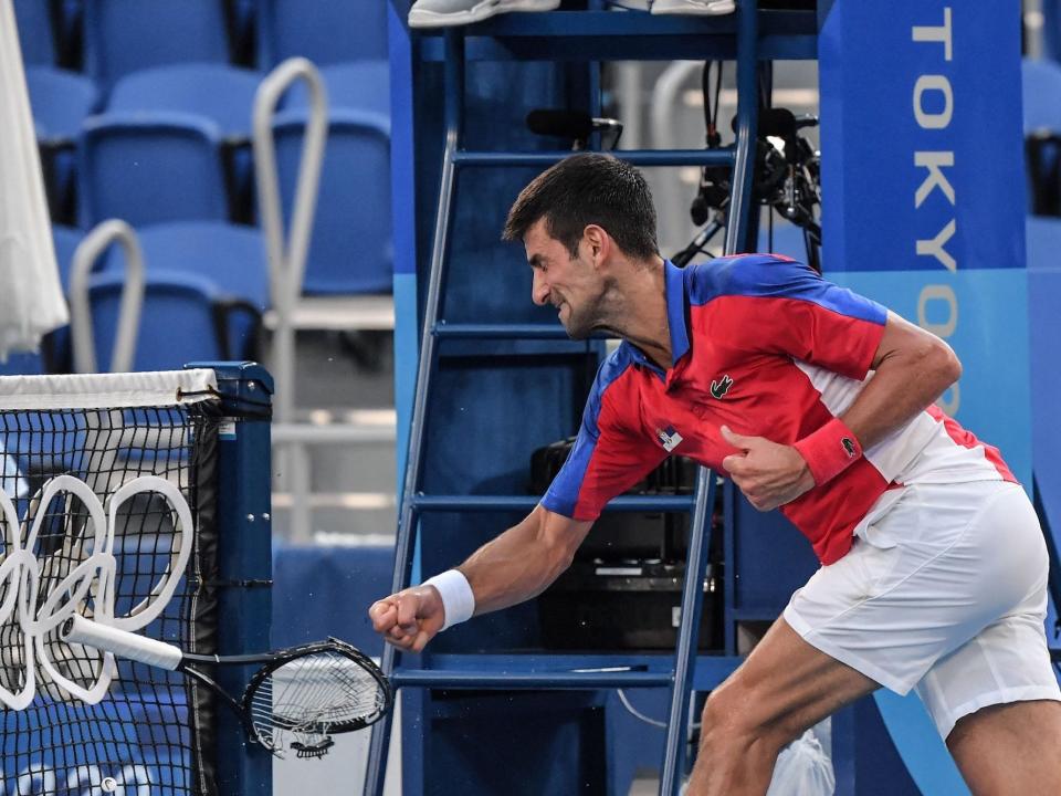 Novak Djokovic smashes his racket into the net at the Tokyo Olympics.