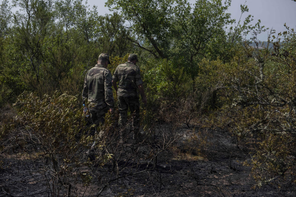 Security forces inspect burned trees in the aftermath of a forest blaze in Laarache, northern Morocco, Friday, July 15, 2022. Fires fanned by strong winds and extreme termperatures have spread across hundred of hectares since Thursday evening. (AP Photo)