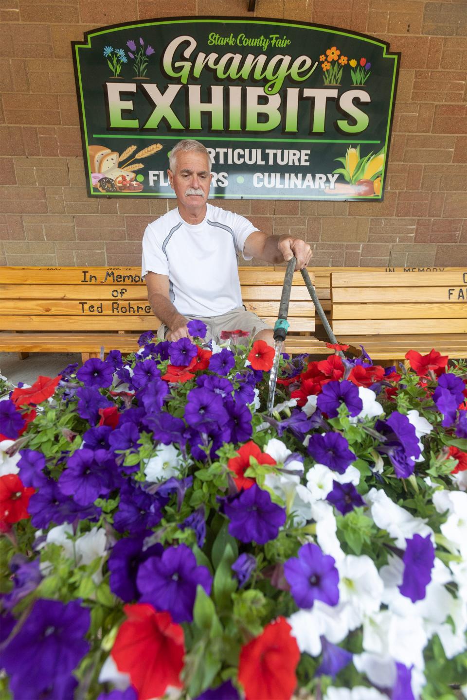 Russ Thorn, a fair director, waters petunias outside the Grange exhibits hall getting ready for the upcoming Stark County Fair.