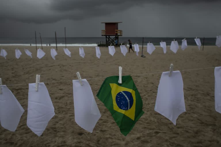 Una bandera brasileña cuelga de un tender en la playa de Copacabana en medio de pañuelos blancos que representan a las personas que han muerto por Covid-19, el viernes 8 de octubre de 2021, en Río de Janeiro