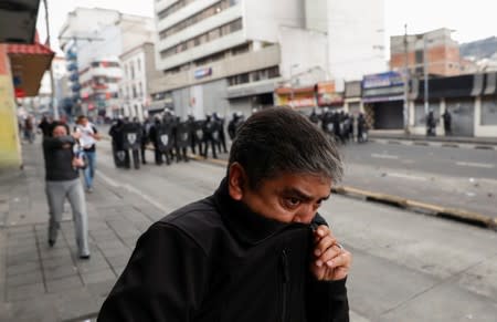 People cover from tear gas as demonstrators clash with police officers during protests after Ecuador's President Lenin Moreno's government ended four-decade-old fuel subsidies in Quito