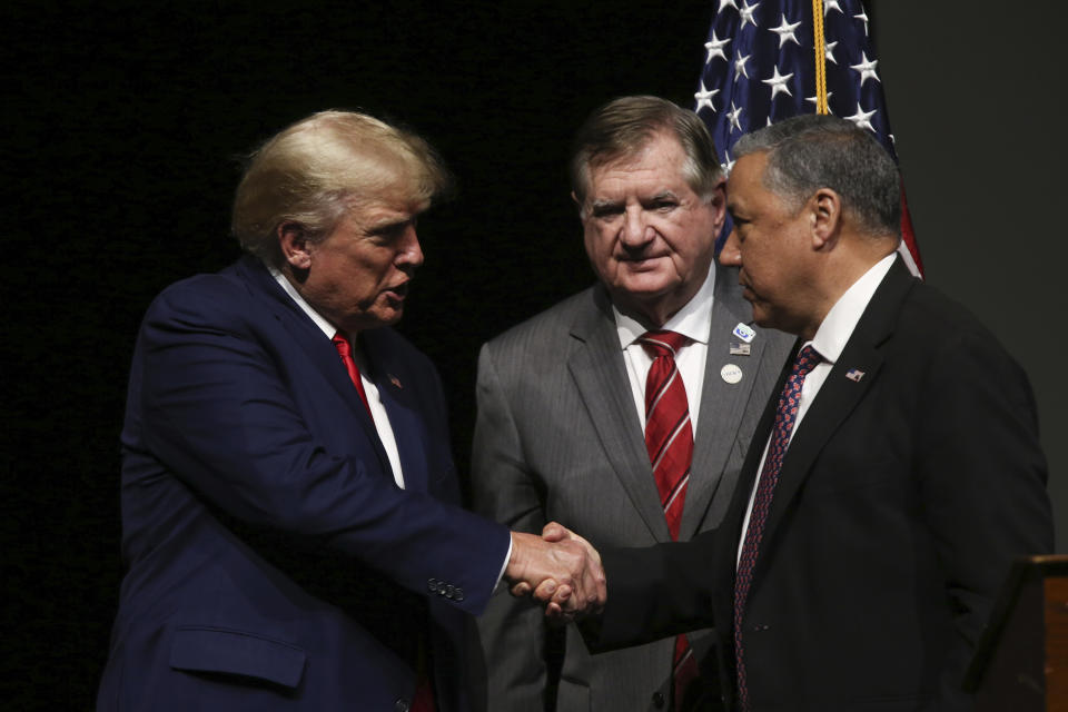 Newly announced Chairman of the New Hampshire GOP Chris Ager, right, shakes hands with former President Donald Trump as outgoing New Hampshire GOP Chairman Stephen Stepanek looks on during the New Hampshire Republican State Committee 2023 annual meeting, Saturday, Jan. 28, 2023, in Salem, N.H. (AP Photo/Reba Saldanha)