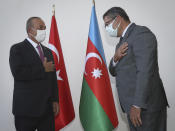 Turkey's Foreign Minister Mevlut Cavusoglu, left, and Azerbaijan's ambassador to Turkey Hazar Zarif İbrahimoğlu greet each other before a meeting, in Ankara, Turkey, Tuesday, Sept. 29, 2020. Cavusoglu on Tuesday renewed Turkey's call for Armenia to withdraw from occupied Azerbaijan territories. (Cem Ozdel/Turkish Foreign Ministry via AP, Pool)