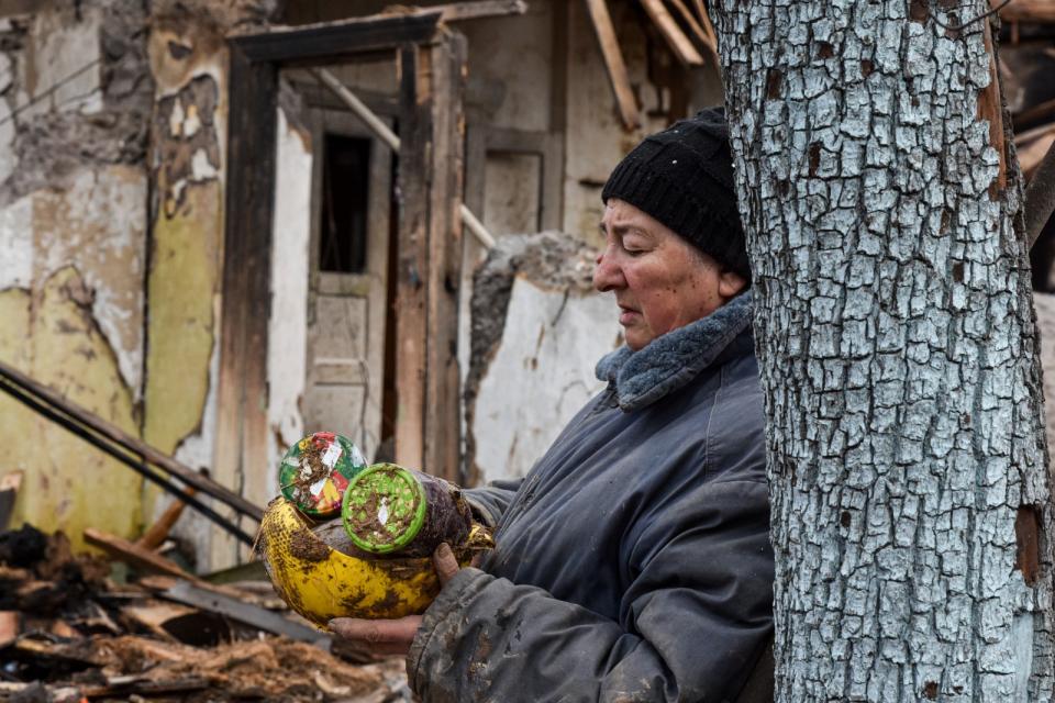 2024 年3 月28日，烏克蘭札波羅熱州，71歲的殷娜（Inna）站在她被俄軍無人機摧毀的房子外，手裡拿著廢墟裡找到的罐頭。美聯社