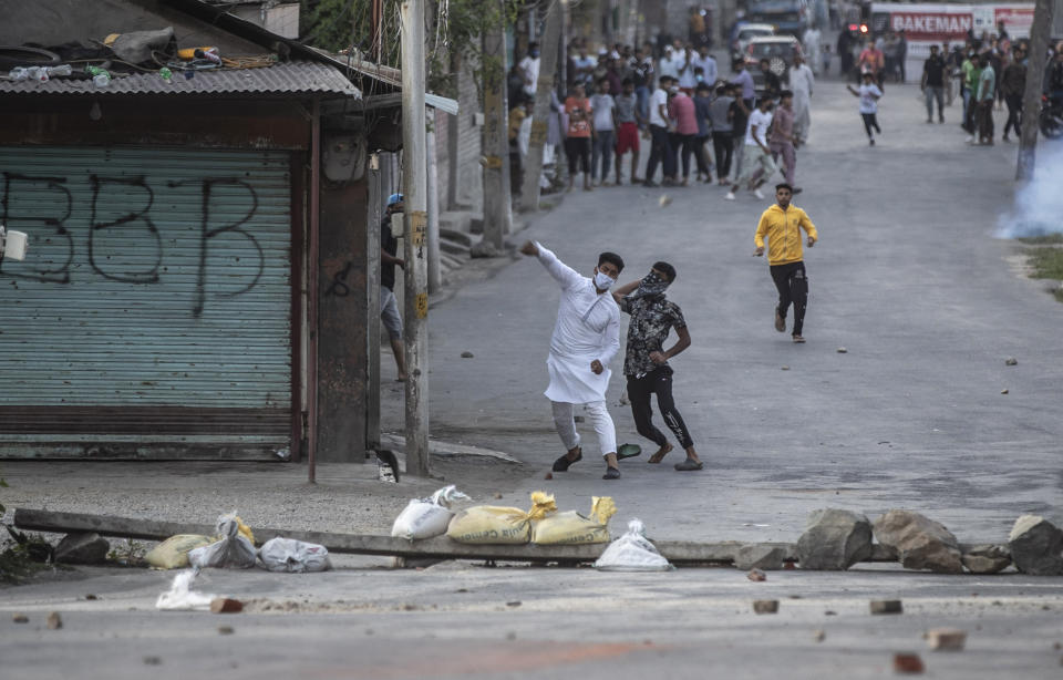 Kashmiri protesters throw stones on Indian paramilitary soldiers and policemen amid tear smoke during a clash in Srinagar, Indian controlled Kashmir, Thursday, Sept. 2, 2021. Indian authorities cracked down on public movement and imposed a near-total communications blackout in disputed Kashmir on Thursday after the death of Syed Ali Geelani, a top separatist leader who became the emblem of the region’s defiance against New Delhi. (AP Photo/ Mukhtar Khan)