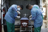 Healthcare workers seal a coffin of a COVID-19 victim patient at Llavallol Dr. Norberto Raúl Piacentini Hospital in Lomas de Zamora, Argentina, Friday, April 23, 2021. Argentina has so far reported more than 67,300 confirmed deaths and more than 3.1 million people sickened by the disease. (AP Photo/Natacha Pisarenko)