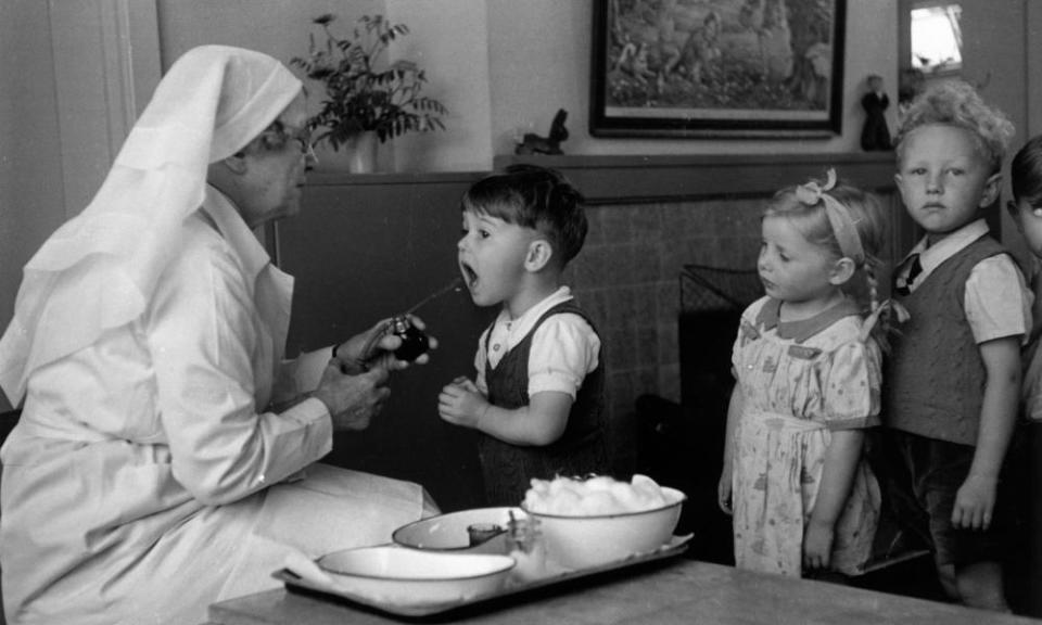 A nursery school nurse giving a pupil a mouth spray in 1944.