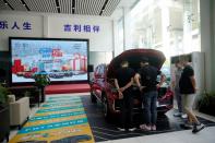 People look at a Geely vehicle at a car dealership in Shanghai