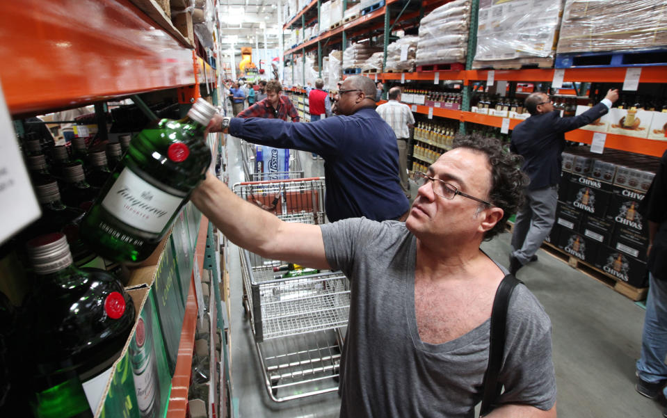 Al Bragalone looks at a bottle of gin as shopper fill a new liquor aisle at a Costco warehouse store Friday, June 1, 2012, in Seattle. Private retailers begin selling spirits for the first time under a voter-approved initiative kicking the state out of the liquor business. The initiative allows stores larger than 10,000 square feet and some smaller stores to sell hard alcohol.(AP Photo/Elaine Thompson)
