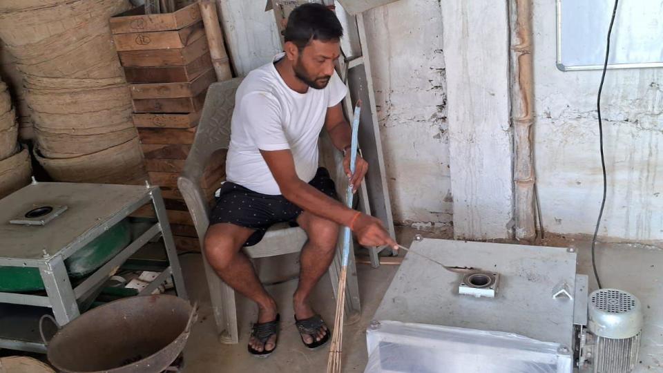 A man feeds fox nuts into a box-like machine where they are popped