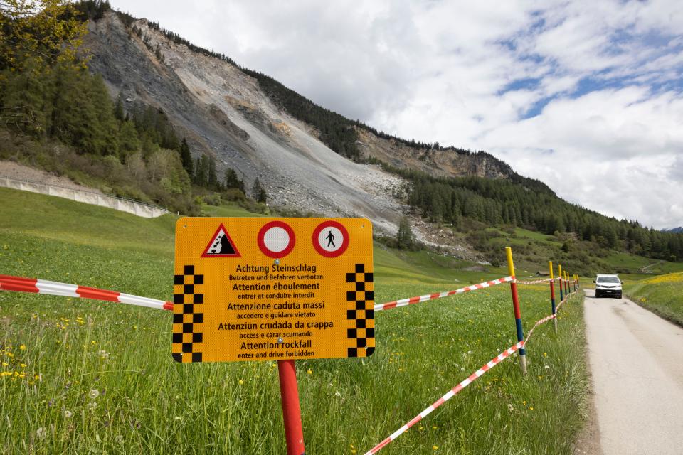 orange sign warns people not to enter a restricted area where rocks on a mountainside threaten to fall in Brienz-Brinzauls, Switzerland