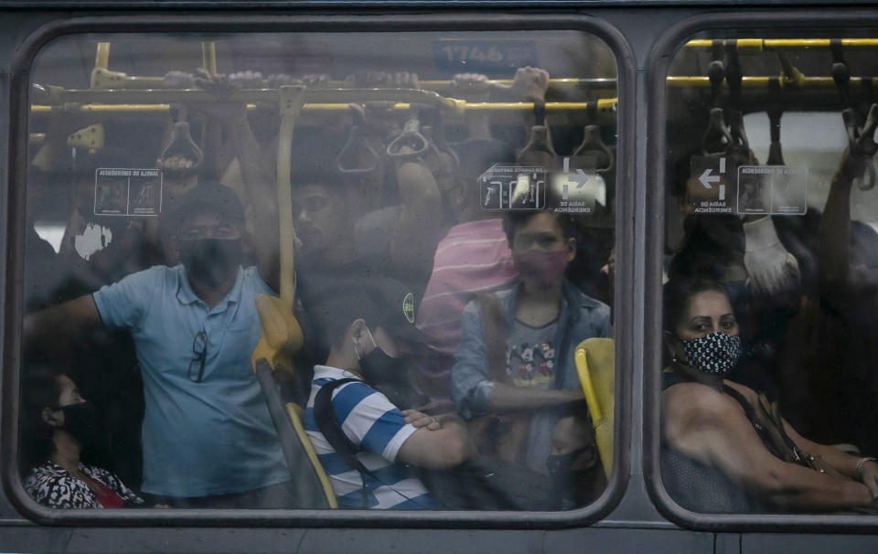 FILE - In this March 30, 2021 file photo, commuters wearing protective face masks amid the COVID-19 pandemic, ride in a crowded public bus, in Rio de Janeiro, Brazil. Public health experts say that restrictions on activity and social distancing can help ease pressure on hospitals' overloaded intensive care units, but that the only long-term solution is mass vaccination in a country of 210 million people that is bigger than the contiguous U.S. (AP Photo/Bruna Prado, File)