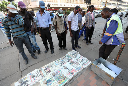 Zimbabweans read newspapers headlines after President Robert Mugabe resigned in Harare, Zimbabwe, November 22, 2017. REUTERS/Mike Hutchings