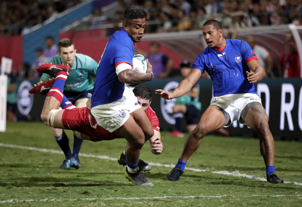 Samoa's Rey Lee-lo, centre, runs past Russia's Tagir Gadzhiev to score a try during the Rugby World Cup Pool A game between Russia and Samoa at Kumagaya Rugby Stadium, Kumagaya City, Japan, Tuesday, Sept. 24, 2019. (AP Photo/Jae Hong)