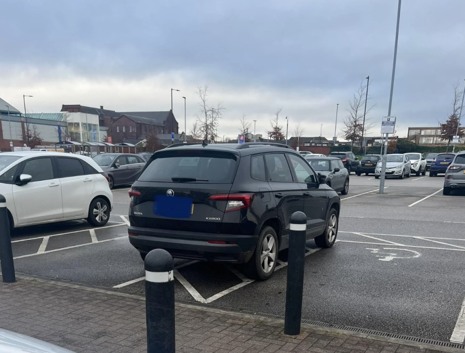 Parking lot scene with various cars including a prominent black SUV poorly parked across two spaces